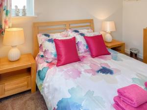 a bedroom with a bed with pink and purple pillows at Beach Retreat - E5558 in Mundesley