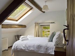 a bedroom with a bed with white sheets and a window at The Mill in Mungrisdale