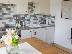 uma cozinha com um vaso de flores sobre uma mesa em Riverbank Cottage em Kirkby Stephen