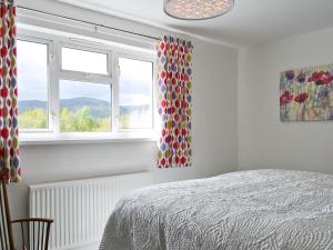 a bedroom with a bed and two windows at 3 Barf Cottages in Portinscale +10 photos