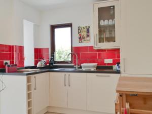 a kitchen with white cabinets and red tiles at 3 Barf Cottages in Portinscale
