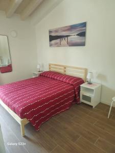 a bedroom with a bed with a red comforter at Red first floor apartment house in Costermano sul Garda