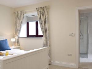 a bathroom with a bed and a shower and a window at Southlands Barn in Saundersfoot