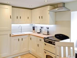 una cucina con mobili bianchi, un lavello e una stufa di River Cottage a Bladnoch