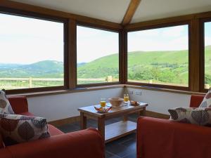 a room with two chairs and a table and windows at Gorsddu in Llanwrthwl