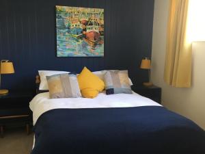 a bedroom with a bed with a painting on the wall at Puffins in Port Isaac