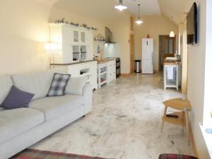 a living room with a couch and a kitchen at Kilbride Beach Cottage in Pollachar