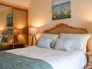 a bedroom with a bed with white sheets and pillows at Kilbride Beach Cottage in Pollachar