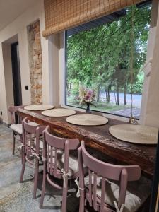 un lungo tavolo in legno con sedie e una finestra di Siedlisko na Roztoczu - Dom pod Lipami 