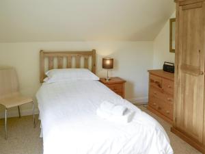 ein Schlafzimmer mit einem großen weißen Bett und einer Kommode in der Unterkunft Birch Cottage in Glenrossal