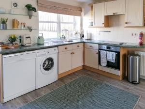 y cocina con lavadora y secadora. en Rosslyn Cottage, en Portmahomack