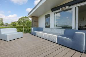 a porch with a blue couch and two white chairs at Sternlaan 8 Kamperland in Kamperland +53 photos