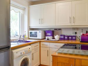 Una cocina con gabinetes blancos y lavadora. en Seaview Cottage, en Bonnavoulin