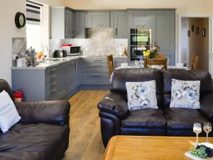 sala de estar con 2 sofás de cuero y cocina en Liftingstane Dairy Cottage, en Closeburn