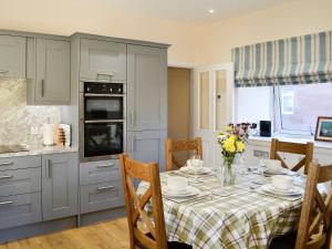una cocina con una mesa con platos y flores. en Liftingstane Dairy Cottage, en Closeburn