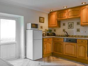 a kitchen with a white refrigerator and wooden cabinets at Lorna's At The Grange - Uk11565 in Mockerkin