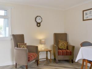 two chairs and a table with a clock on the wall at Lorna's At The Grange - Uk11565 in Mockerkin
