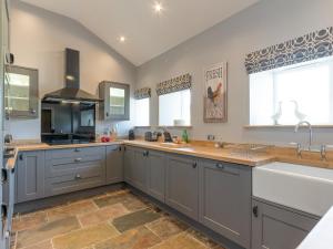 a large kitchen with gray cabinets and a sink at Abraham's Cottage in Low Eskcleth +11 photos