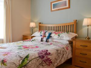 ein Schlafzimmer mit einem Bett mit Blumen darauf in der Unterkunft Kilbride Cottage in Pollachar