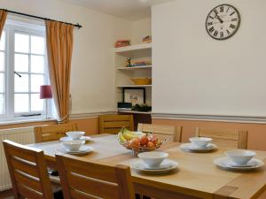 ein Esstisch mit einer Obstschale und einer Uhr in der Unterkunft Old Town Cottage in Sidmouth