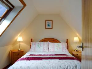 a bedroom with a bed with pink and white pillows at Tote Cottage in Skeabost +9 photos