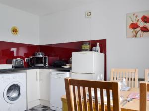 a kitchen with a white refrigerator and a table with chairs at Tote Cottage in Skeabost