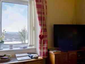 a living room with a television and a window at Tote Cottage in Skeabost
