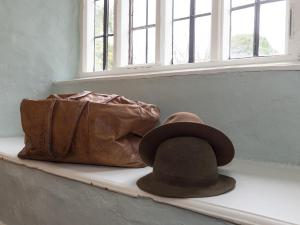 un chapeau et un porte-monnaie assis sur un rebord de fenêtre dans l'établissement The Old Priory Cottage, à Dunster