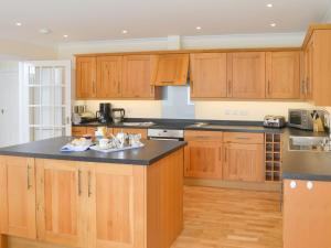 a kitchen with wooden cabinets and a black counter top at Driftwood in Port Isaac