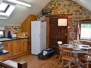 a kitchen with a table and a white refrigerator at The Old Coach House in Woolfardisworthy