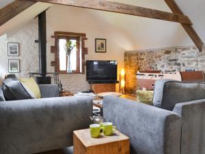 a living room with two couches and a tv at The Old Coach House in Woolfardisworthy