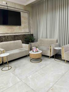 a living room with couches and tables and a tv at فندق الأصالة البكية توصيل مجاني الى الحرم - ALAsalah ALBakkiya Hotel Free Shuttel Service in Al Masfalah
