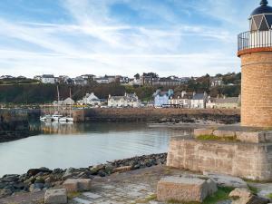 un faro accanto a uno specchio d'acqua con barche di Kirklauchline Cottage a Portpatrick