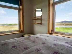 a bedroom with a bed and two windows at Altabrug in Howmore