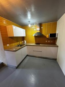 a small kitchen with white cabinets and yellow tiles at Quinta de Águas Mortas in Gestaco