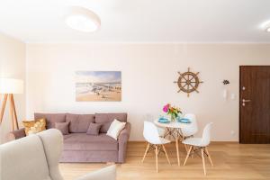a living room with a purple couch and a table at Apartament Bursztynowy in Rowy