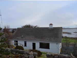 a white house with a roof and a body of water at Cuckoos Nest in Cove