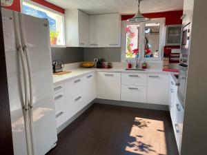 a white kitchen with white cabinets and red walls at Los Veroles in Agaete
