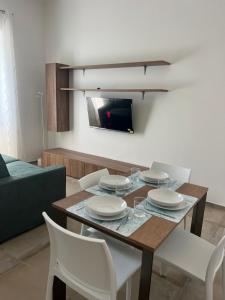 a dining room table with white chairs and a tv at DGD house in Carrara