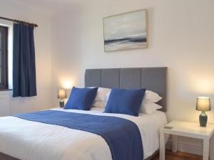 ein Schlafzimmer mit einem großen Bett mit blauen Kissen in der Unterkunft Pembroke Cottage in Pembroke + 3 Fotos