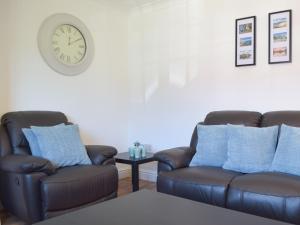 ein Wohnzimmer mit 2 Stühlen und einer Uhr an der Wand in der Unterkunft Pembroke Cottage in Pembroke