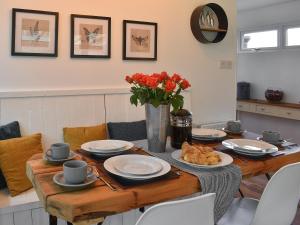 una mesa de comedor con platos y un jarrón de flores en The Wood House, en Buckfastleigh