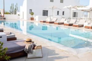 Una piscina con tumbonas y un sombrero al lado. en 18 Grapes Hotel, en Agios Prokopios