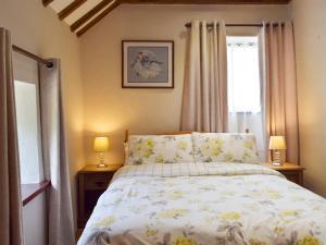 ein Schlafzimmer mit einem Bett mit zwei Nachttischen und zwei Lampen in der Unterkunft Old Rectory Cottage - Dinas Country Club in Dinas