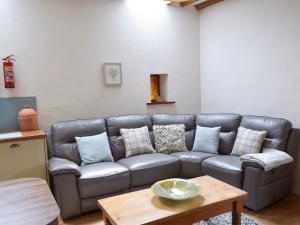 ein Wohnzimmer mit einer Ledercouch und einem Tisch in der Unterkunft Old Rectory Cottage - Dinas Country Club in Dinas