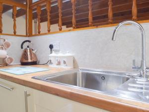 eine Küchentheke mit einer Edelstahlspüle in der Unterkunft Hay Barn - Dinas Country Club in Dinas