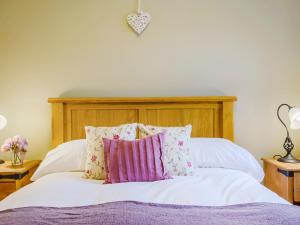 a bedroom with a bed with a wooden headboard and pillows at Ysgubor - Uk31389 in Caeathro +11 photos