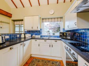 a kitchen with white cabinets and blue tiles at Ysgubor - Uk31389 in Caeathro