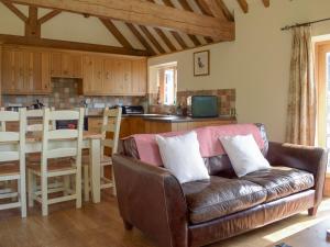 a living room with a leather couch and a kitchen at Talog Barn-Uk31366 in Tregynon