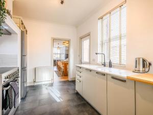 a kitchen with white cabinets and a table at Wisteria Cottage in Heacham